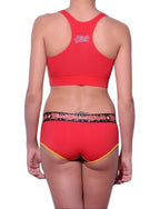 Full length rear view of a model wearing Ginch Gonch red atomic fireballs sports bra cotton stretch top activewear with a white background.
