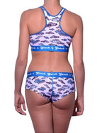 Rear view of a model wearing Ginch Gonch Busted Gogo Briefs with a matching sports bra and an an all-over police car chase print.