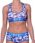 Ginch Gonch Busted Sports Bra with a matching bottom, featuring a vibrant all-over police car chase print and a flexible performance fit worn by a model.