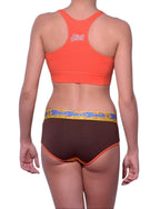 Full length rear view of a model wearing Ginch Gonch yellow and brown lemon head cotton stretch boyfriend brief with an orange sports bra.