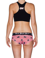 From behind of a model wearing Ginch Gonch Wild Bulls Women's Gogo Briefs in red and white bull stripe print, gogo cut, 4-way stretch fabric with black sports bra.