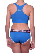 Viewed from behind of a model wearing Ginch Gonch Blue Coconuts boyfriend briefs showing full seat coverage and anti-muffin waistband in electric blue with matching sports bra
