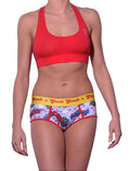 Ginch Gonch Under-Man Women's boyfriend briefs in yellow, red and purple fun superhero print, 4-way stretch cotton full coverage cut, worn by a model paired with orange sports bra.