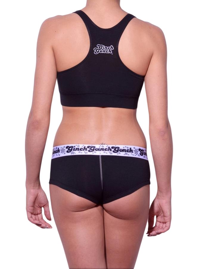 Viewed from behind of a model wearing Ginch Gonch Black Magic gogo briefs showing anti-muffin waistband and solid black cotton bikini cut
