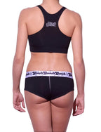 Viewed from behind of a model wearing Ginch Gonch Black Magic gogo briefs showing anti-muffin waistband and solid black cotton bikini cut