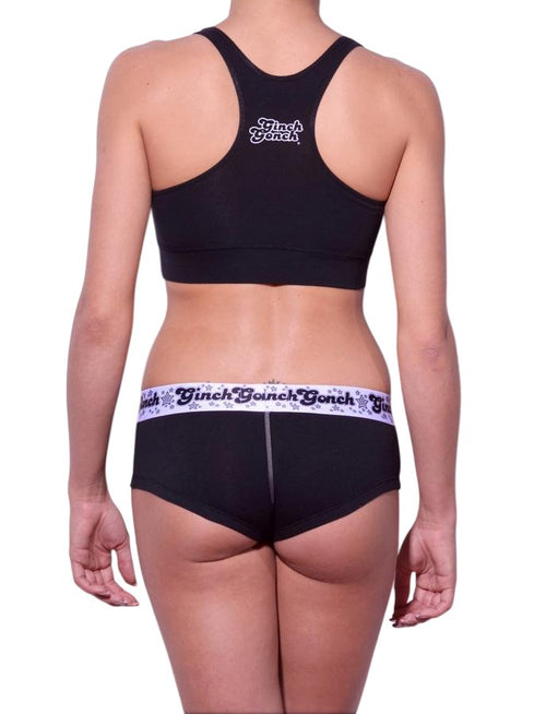 Viewed from behind of a model wearing Ginch Gonch Black Magic gogo briefs showing anti-muffin waistband and solid black cotton bikini cut
