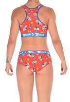 From the back, full body view of Ginch Gonch GG EMT gogo briefs showing anti-muffin waistband and medical print stretch cotton along with a sports bra.